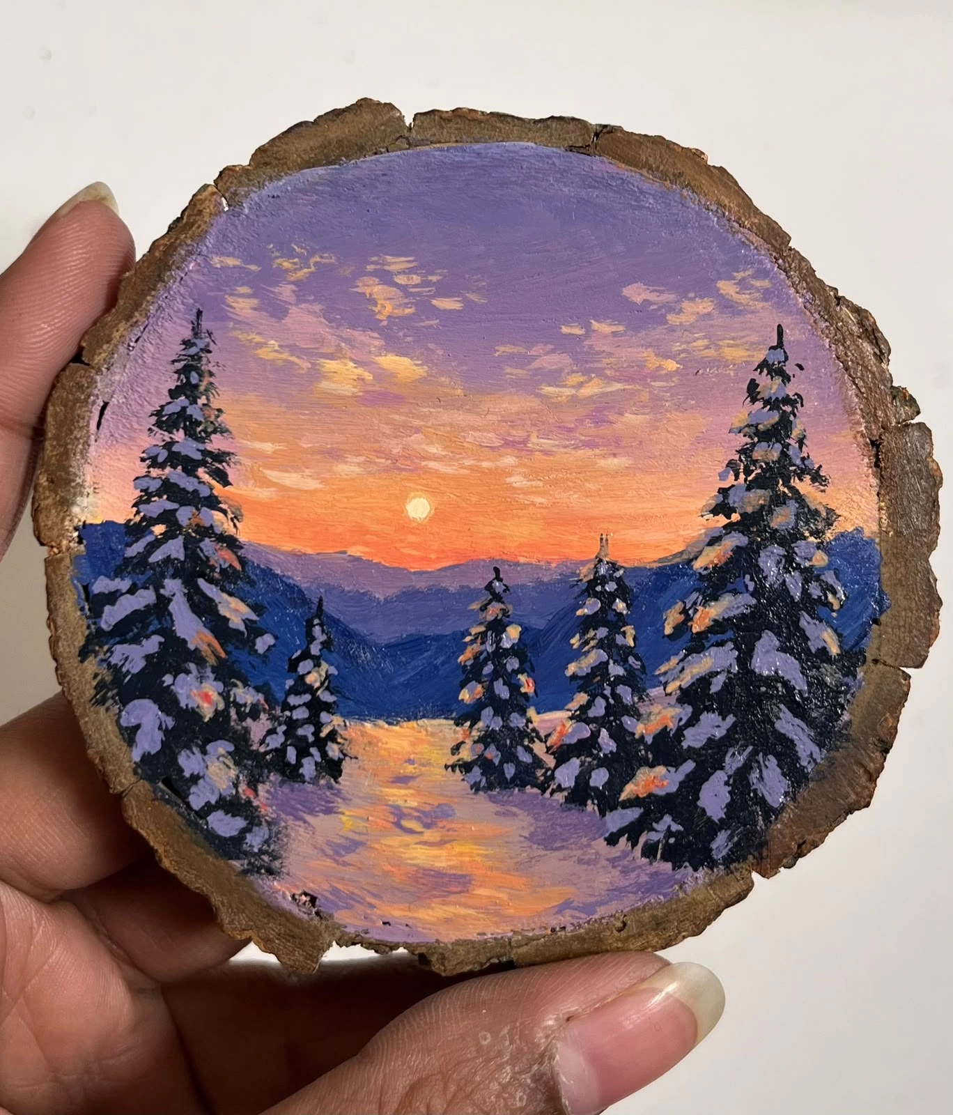 Winter sunset painted on a round wood slice with snowy trees